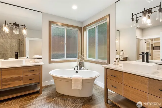 a bathroom with a double vanity sink mirror and bathtub