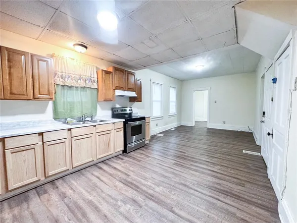 a kitchen with granite countertop wooden floors a sink cabinets and appliances