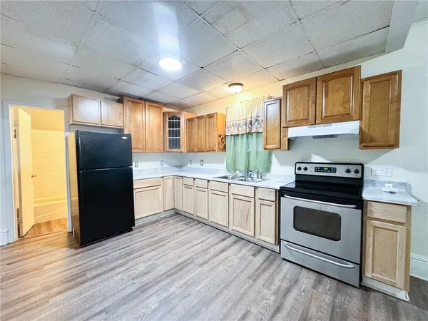 a kitchen with granite countertop stainless steel appliances a refrigerator cabinets and wooden floor