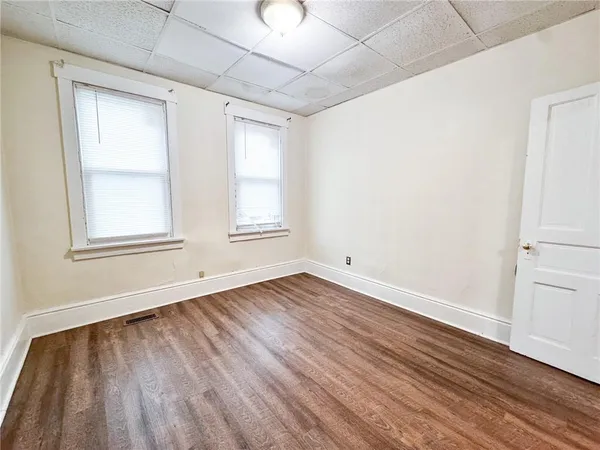 an empty room with wooden floor and windows