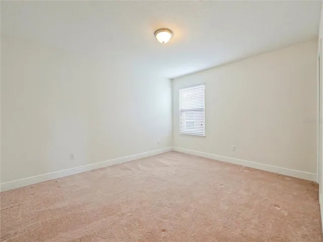 a view of an empty room with closet and a window