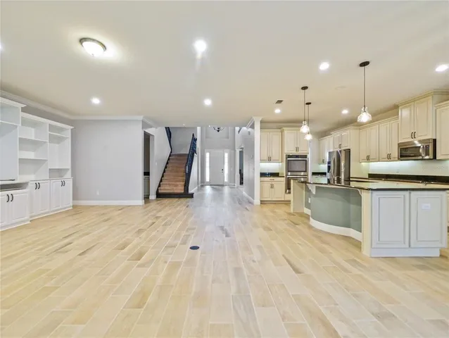 a large kitchen with a large counter top a sink stainless steel appliances and cabinets