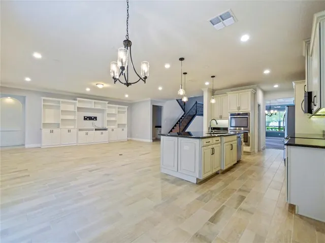 a large kitchen with stainless steel appliances kitchen island a refrigerator and a view of living room