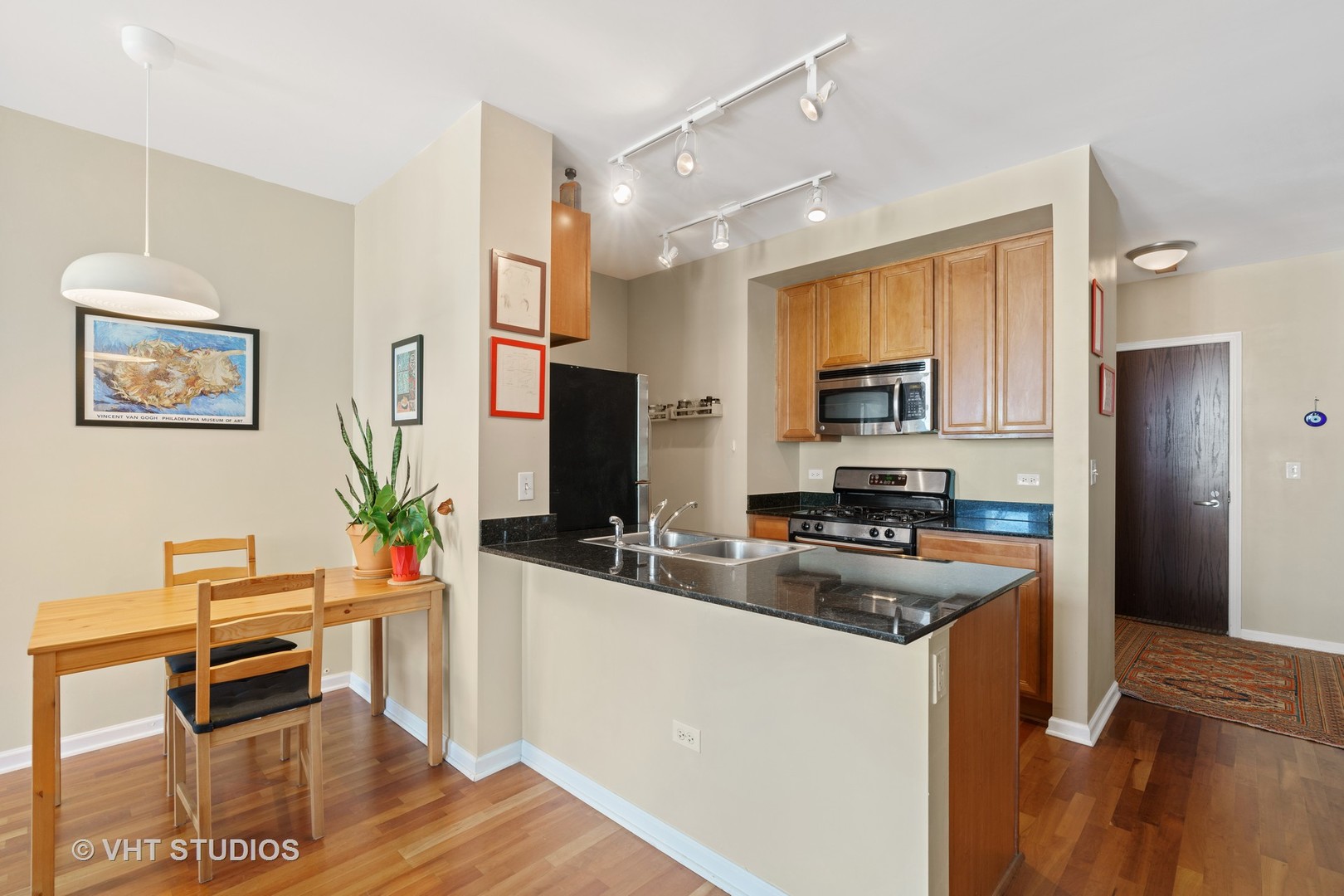 1255 South State Street, Unit 1809 Chicago, IL 60605 - Photo 4 of 11 a kitchen with a refrigerator a stove and a dining table with wooden floor