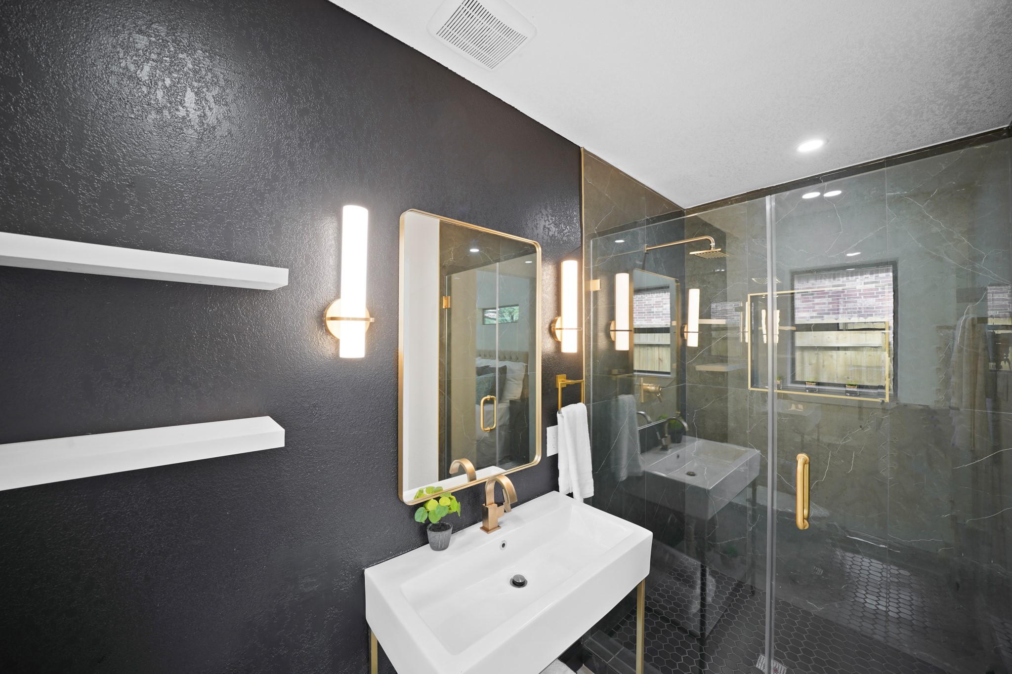 4813 Hummingbird Street Houston, TX 77035 - Photo 15 of 50 High End Finishes abound in this Modern Primary Bath featuring a "Swiss Madison" Vanity w/White Porcelain Sink, Champagne Brass Style Faucet, Dual Brushed Brass Wall Sconces, Brass Style Framed Mirror, Brushed Natural Brass Towel Rack, Towel Ring, & Paper Holder. Pamper Yourself in the Walk in Frameless Glass Shower w/Metallic Slate Marble Style Tile Surround, Onyx Hexagon Tile Floor, Brass Style Rain Shower Head & Brass Style Door Handle. Light Grey Italian Floors complete the Look in this Elegant Bath!