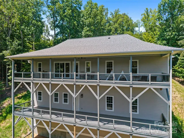 a view of a house with wooden deck and a large tree
