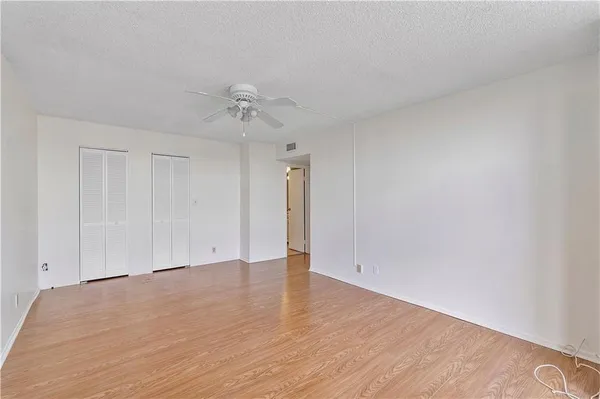 an empty room with wooden floor and ceiling fan
