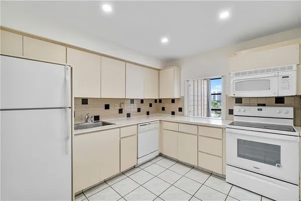 a kitchen with white cabinets sink and white appliances