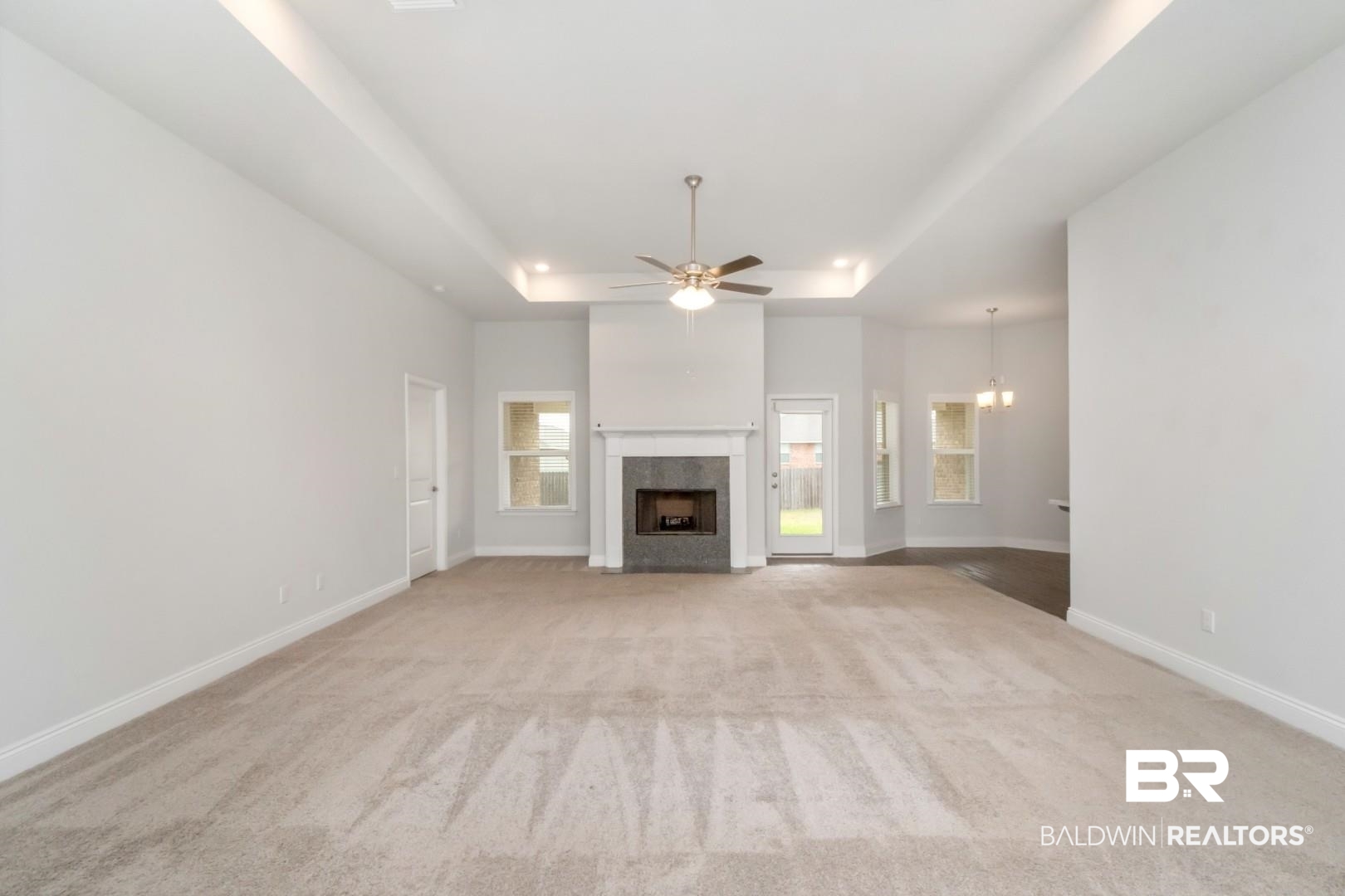 6632 Monarch Circle Mobile, AL 36618 - Photo 3 of 32 Unfurnished living room featuring a tray ceiling, light colored carpet, a ceiling fan, and a high end fireplace