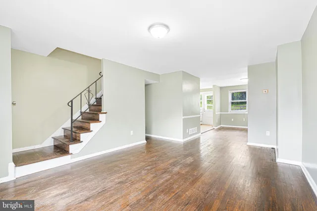 a view of an empty room with wooden floor and stairs