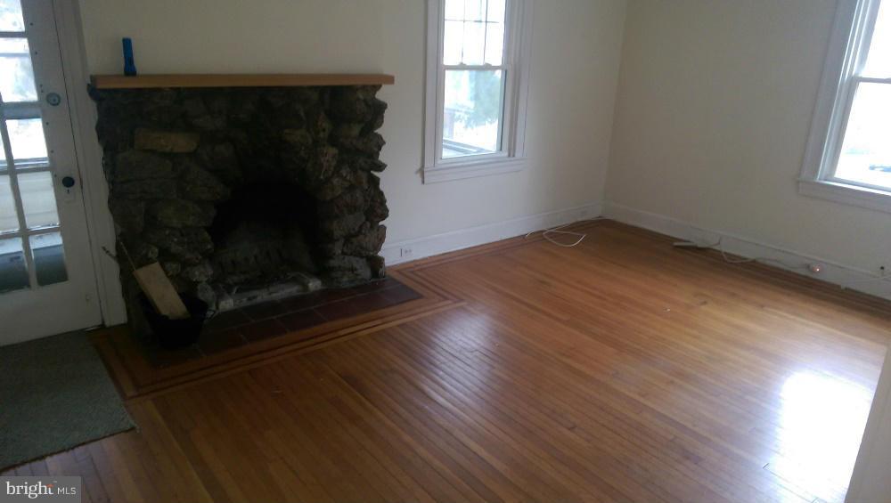6000 Falls Road Baltimore, MD 21209 - Photo 3 of 13 an empty room with wooden floor a fireplace and windows