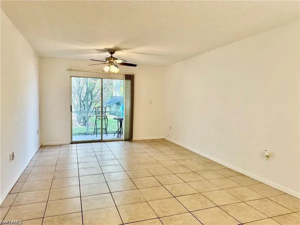 a view of an empty room and window & chandelier fan