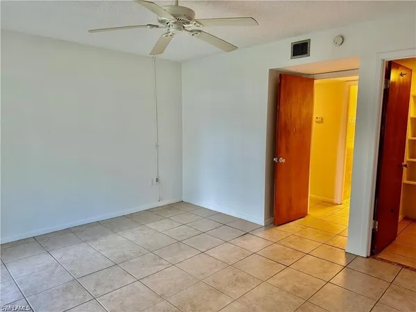 an empty room with windows and fan