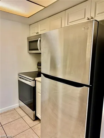 a view of a refrigerator in kitchen and stainless steel appliances wooden cabinet