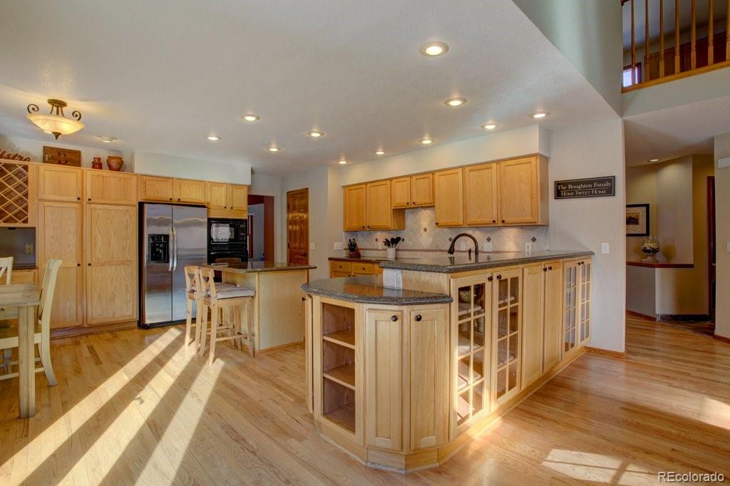 2364 Stratford Court Highlands Ranch, CO 80126 - Photo 9 of 35 a kitchen with stainless steel appliances kitchen island granite countertop a stove top oven a sink a refrigerator and white cabinets with wooden floor