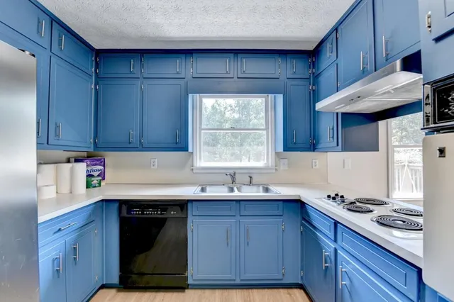 a kitchen with granite countertop wood cabinets stainless steel appliances a sink and a window