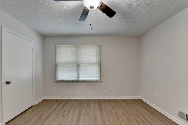 an empty room with a window and a ceiling fan