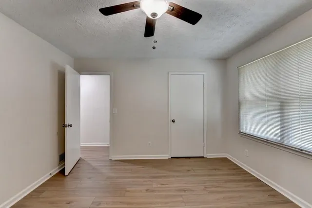 a view of an empty room with wooden floor and a window