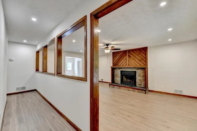 a view of an empty room with wooden floor fireplace and a window