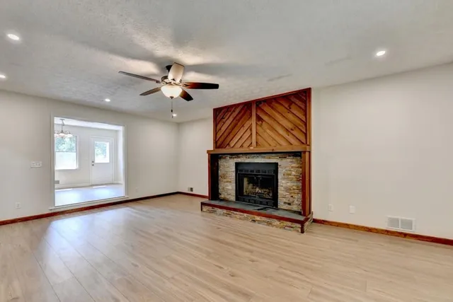 an empty room with windows fireplace and wooden floor
