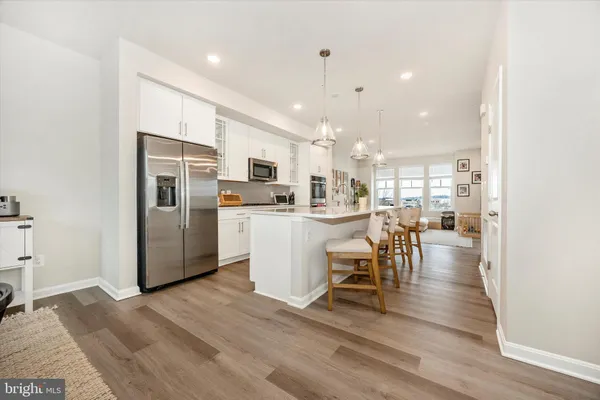 a kitchen with stainless steel appliances a dining table chairs stove refrigerator and cabinets