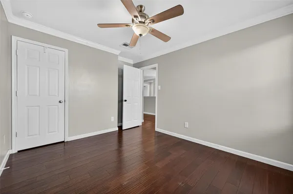 a view of empty room with wooden floor and fan