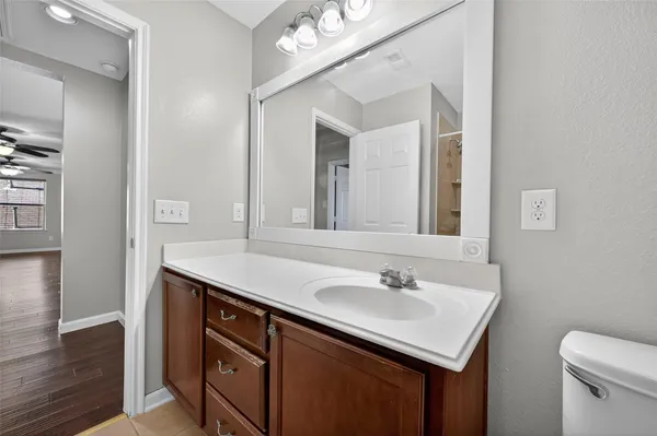 an empty room with wooden floor ceiling fan and windows