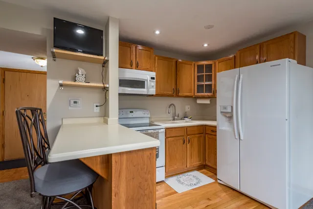 a kitchen with stainless steel appliances a refrigerator a sink a stove a table and chairs