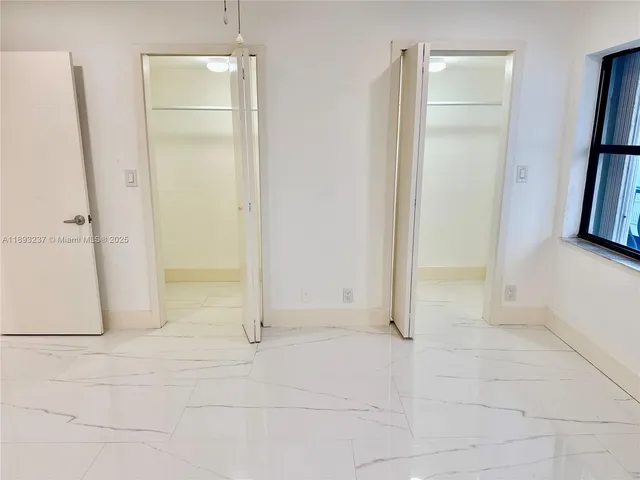 an empty room with windows and refrigerator