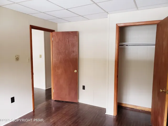a view of an empty room with wooden floor and closet