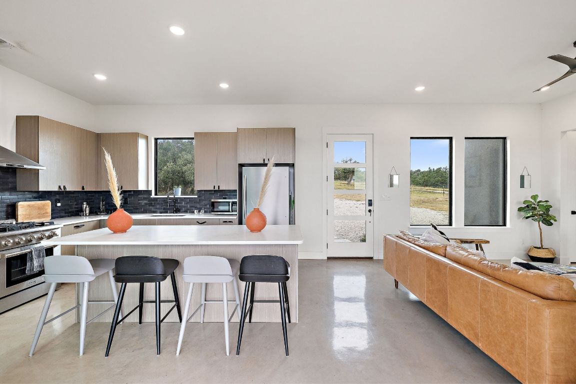 11 Sacramento Boerne, TX 78006 - Photo 7 of 40 Kitchen featuring a kitchen breakfast bar, concrete floors, tasteful backsplash, a center island, and appliances with stainless steel finishes