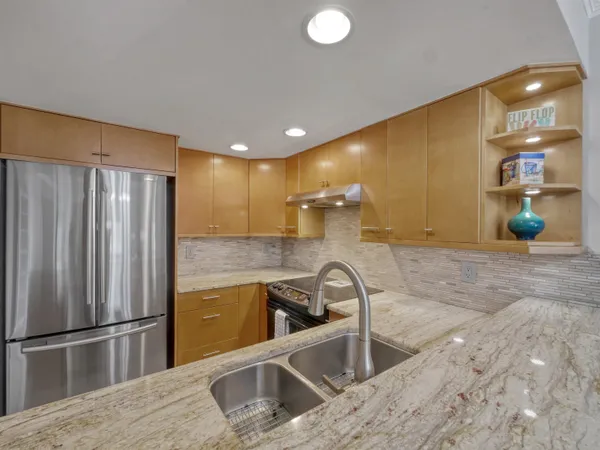 a kitchen with stainless steel appliances granite countertop a sink and a refrigerator