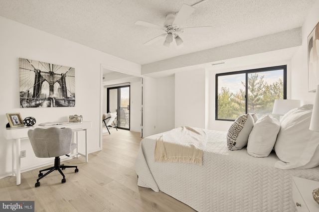 a bedroom with a bed a chair and a large mirror next to a window