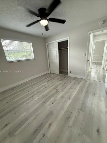 an empty room with wooden floor windows and a ceiling fan