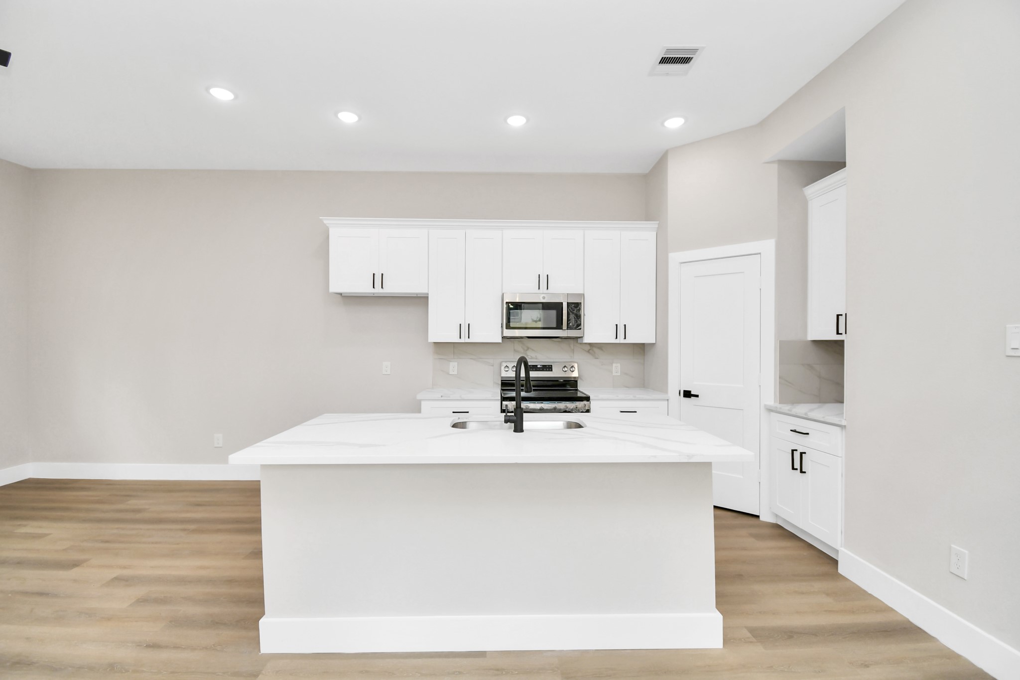 8409 Sunnyhill Street Houston, TX 77088 - Photo 2 of 13 a large white kitchen with kitchen island a sink stainless steel appliances and cabinets
