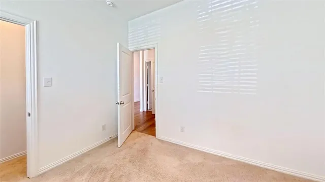 an empty room with a chandelier fan and windows
