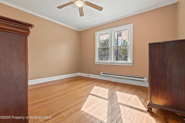 a view of an empty room with a window and wooden floor