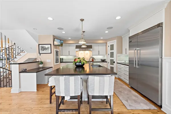 a large kitchen with a table chairs refrigerator and wooden floor