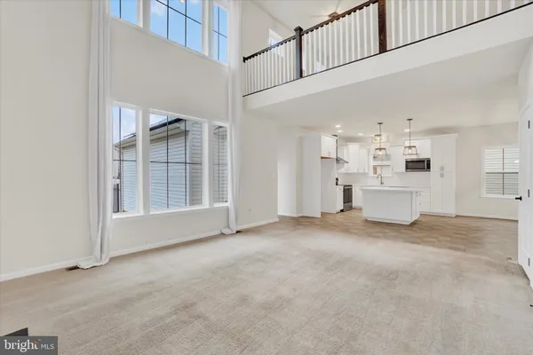 a view of an empty room with kitchen and window