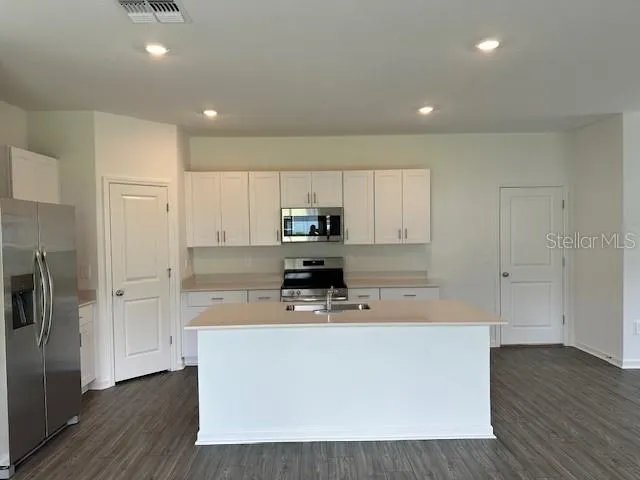 a large kitchen with stainless steel appliances a large counter top and a stove top oven