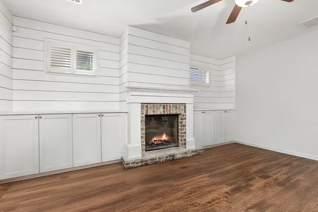 a view of an empty room with wooden floor fireplace and a window