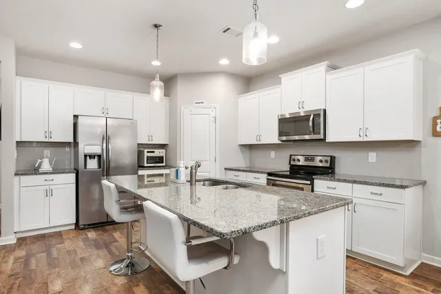 a kitchen with stainless steel appliances granite countertop a stove refrigerator a microwave oven with a dining table and chairs