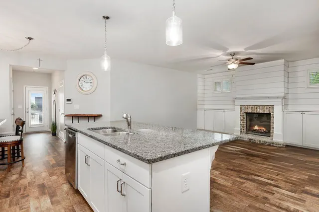 a hall with kitchen island a fireplace wooden floor and a ceiling fan
