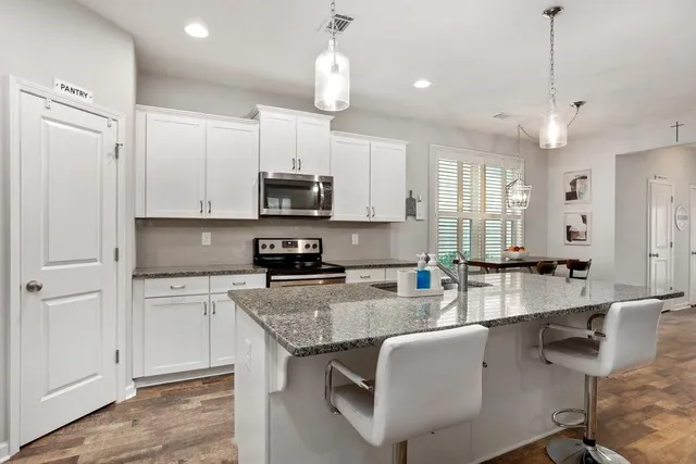 a large kitchen with kitchen island granite countertop a stove a sink a center island a counter space and cabinets
