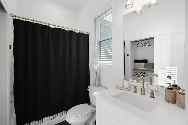 a bathroom with a sink a toilet a mirror and shower curtain