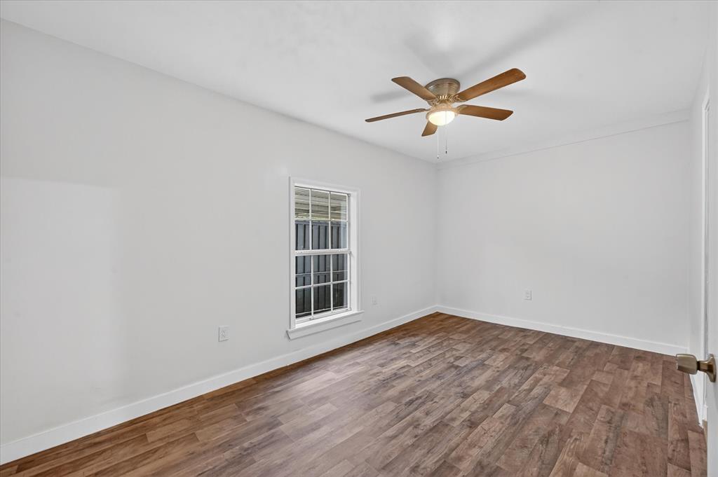 538 Pemberton Hill Road Dallas, TX 75217 - Photo 16 of 31 Room featuring wood-finish flooring, white baseboards, a single window with blinds, and a ceiling fan with integrated lighting