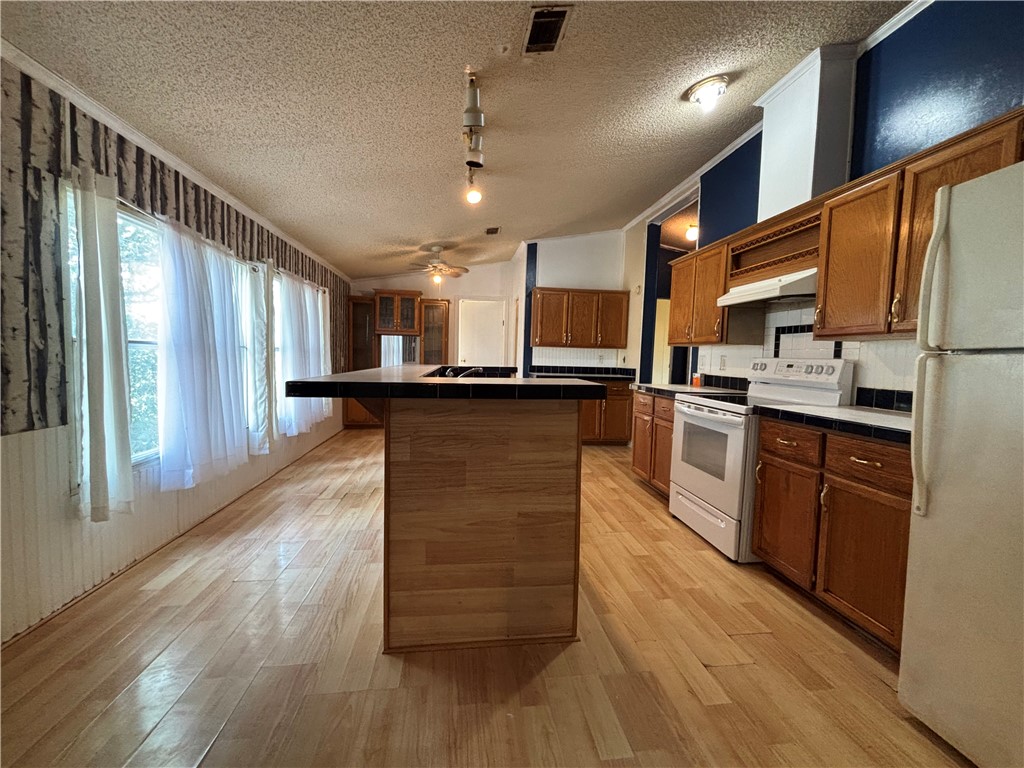 568 Jennifer Loop Orange Grove, TX 78372 - Photo 24 of 35 a kitchen with stainless steel appliances kitchen island granite countertop wooden floors wooden cabinets and sink
