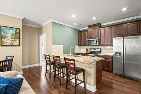 a kitchen with stainless steel appliances granite countertop a dining table chairs refrigerator and microwave