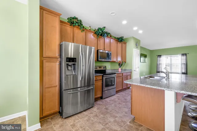 a kitchen with kitchen island granite countertop a sink refrigerator and cabinets