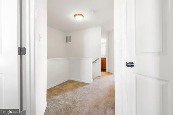 a view of a hallway with white walls and stairs